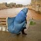 A burqa-clad Afghan woman crosses a bridge following flash floods in Herat province