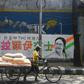 Delivery men walk past a mural bearing Chinese characters in support of a Trinamool Congress candidate in Kolkata