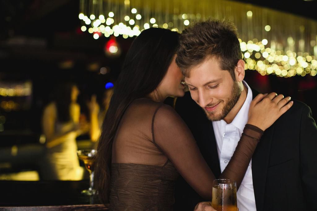 Smiling couple whispering at bar