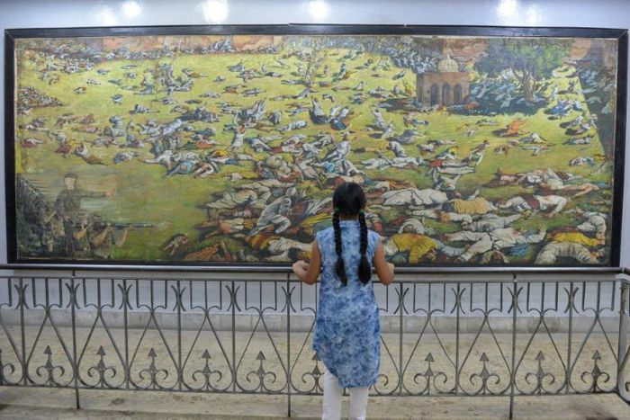 An Indian girl looks at a painting of the Amritsar massacre in 1919 when British troops opened fire on Indian protesters in the northern city, killing 400 according to colonial era records. India puts the toll much higher, at nearer 1,000