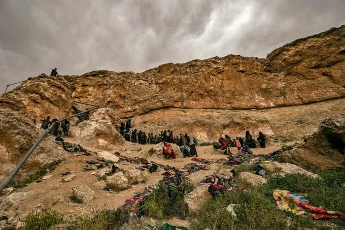 Suspected members of the Islamic State (IS) group exit with children from the village of Baghouz in the eastern Syrian province of Deir Ezzor