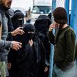 Members of the Syrian Democratic Forces stand guard over veiled women in al-Hol camp in northeastern Syria, which houses relatives of Islamic State group members