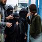Members of the Syrian Democratic Forces stand guard over veiled women in al-Hol camp in northeastern Syria, which houses relatives of Islamic State group members