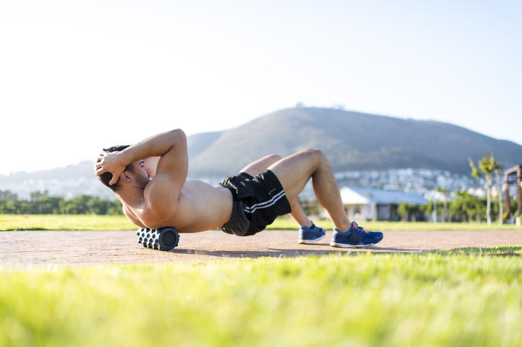 Young man releasing muscle tension using a foam roller