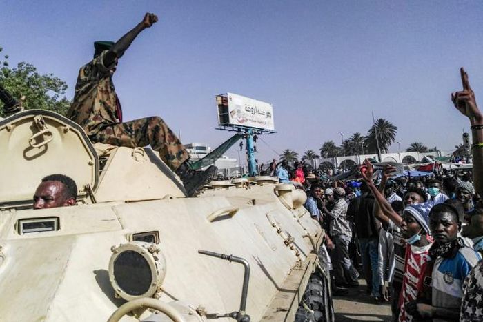 Sudanese protesters salute a military armoured vehicle at a demonstration in front of the army headquarters in Khartoum, as some ranks appear to be tiling towards the rallies