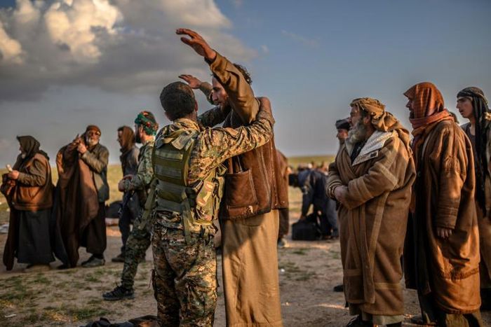 Men suspected of being Islamic State group fighters are searched after leaving the jihadists' last holdout of Baghouz in Syria