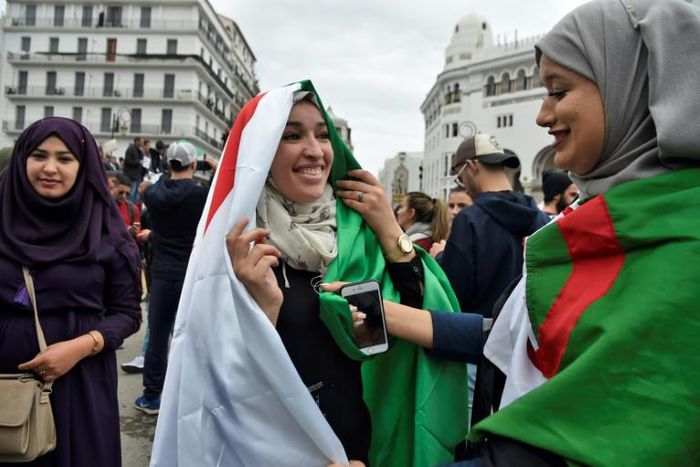 Protesters wear the Algerian national flag in the capital Algiers on March 8, 2019