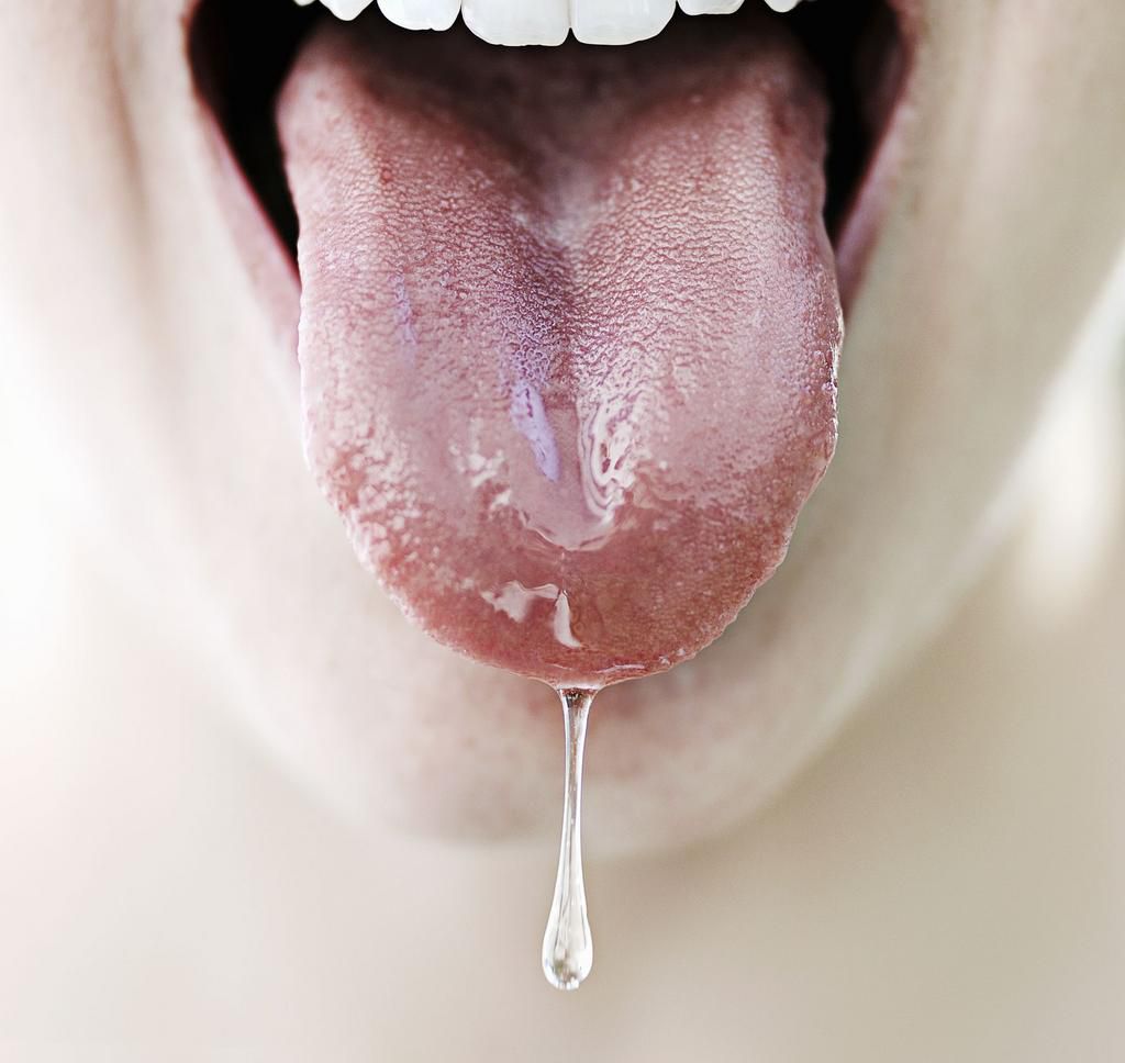 Woman's tongue dripping with saliva, close-up