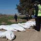 Workers gather bodies found in another mass grave near the northern Syrian city of Raqa on February 19, 2019