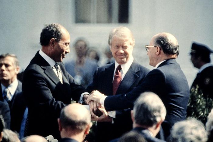 US President Jimmy Carter (C) congratulates Egyptian President Anwar Sadat (L) and Israeli Premier Menachem Begin (R) in three-way handshake on the White House lawn after the signing of the historic peace treaty