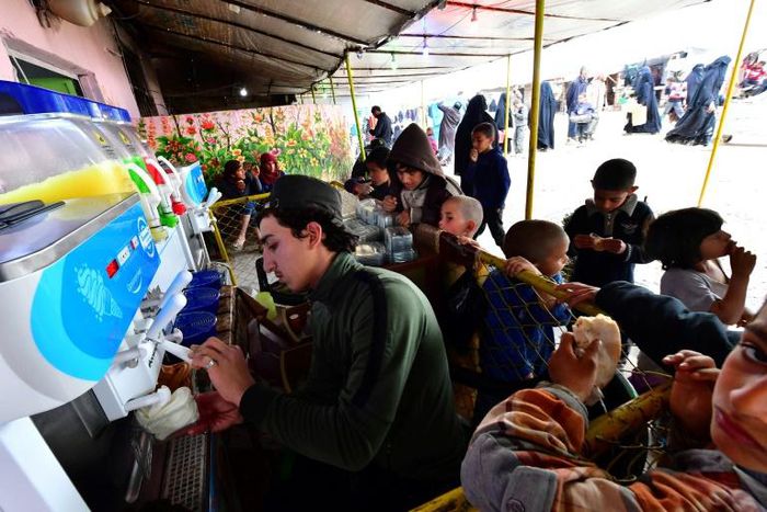 Children buy ice cream from a shop in a market at Al-Hol camp for displaced people in northeastern Syria