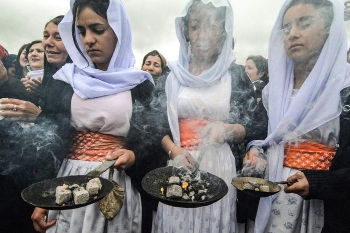 Members of the Yazidi minority take part in a ceremony during the exhumation of a mass grave of victims of the Islamic State group in northern Iraq