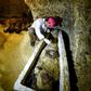 An archaeologist brushes a newly-discovered mummy laid inside a sarcophagus, part of a collection found in burial chambers dating to the Ptolemaic era (323-30 BC) in February 2019