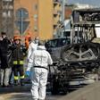 Forensic policemen and firefighters work near the wreckage of a school bus after rescuing some 50 children as the driver torched the vehicle, southeast of Milan.