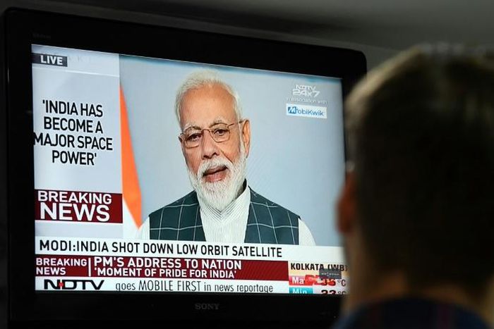 A man watches Indian Prime Minister Narendra Modi's address to the nation on a local news channel declaring his country is a space power after destroying a low-orbiting satellite