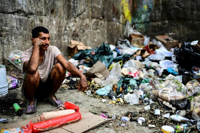 A man waits to get some food at a garbage dump in Las Minas de Baruta neighborhood, Caracas, Venezuela, on March 14, 2019