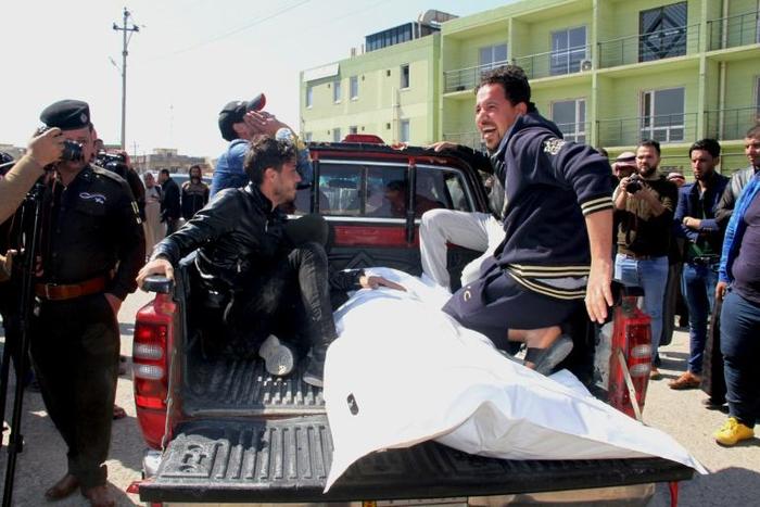 Relatives mourn over the body of a passenger who died in a ferry accident while crossing the Tigris river outside a morgue in the northern Iraqi city of Mosul