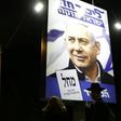 A woman and an ultra-Orthodox Jewish man walk past a billboard displaying Israeli Prime Minister Benjamin Netanyahu in Jerusalem