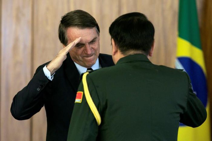 Brazilian President Jair Bolsonaro (L) salutes a Chinese military official as new diplomats presented their on Friday