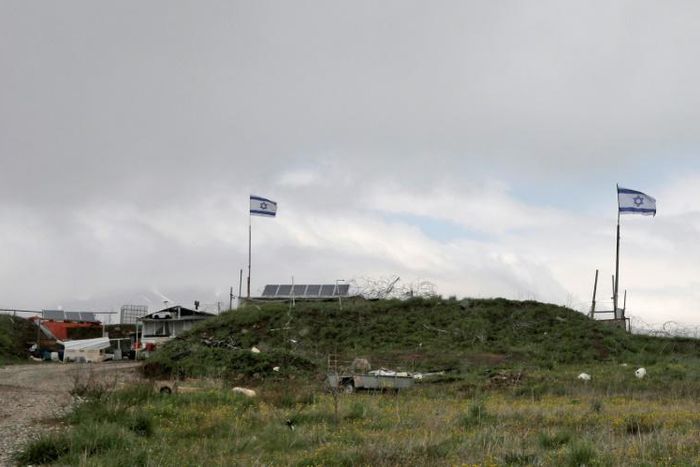 Israeli flags fly over a military base near the border fence with Syria in the Israeli-annexed Golan Heights, south of the Druze village of Majdal Shams