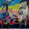Supporters of Venezuelan President Nicolas Maduro sit backdropped by a mosaic depicting their leader, during a demonstration in Caracas on March 16, 2019