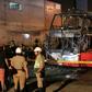 Police stand around the charred remains of a bus that caught fire in Lima killing 20 people