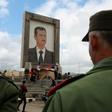 Protesters hold a national flag under a portrait of Syrian President Bashar al-Assad in the Syrian Golan Heights, during a demonstration on March 26, 2019
