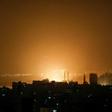 The sky above buildings on the Gaza Strip glows orange during an Israeli air strike in Gaza City late on March 14
