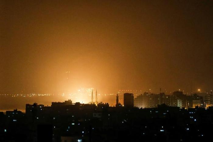 The sky above buildings on the Gaza Strip glows orange during an Israeli air strike in Gaza City late on March 14