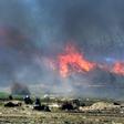 Men believed to be Islamic State fighters walk amidst flames and smoke in the jihadist group's last remaining position in the village of Baghouz in eastern Syria on March 18, 2019