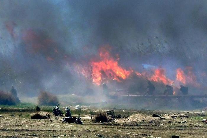 Men believed to be Islamic State fighters walk amidst flames and smoke in the jihadist group's last remaining position in the village of Baghouz in eastern Syria on March 18, 2019