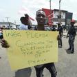 A protester holds a placard reading "Please conclude the elections for the sake of peace" during a demonstration against the suspension of governorship elections in Port Harcourt, Rivers state
