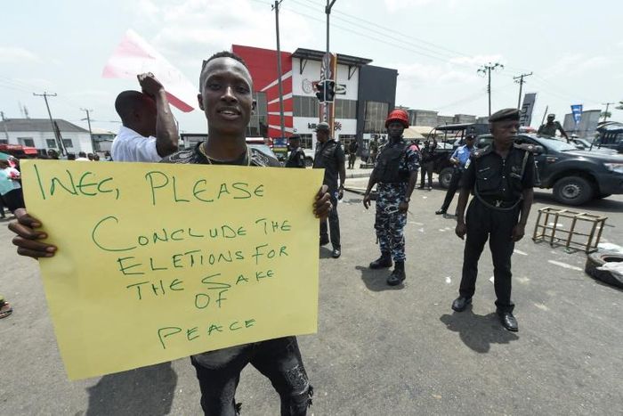 A protester holds a placard reading "Please conclude the elections for the sake of peace" during a demonstration against the suspension of governorship elections in Port Harcourt, Rivers state