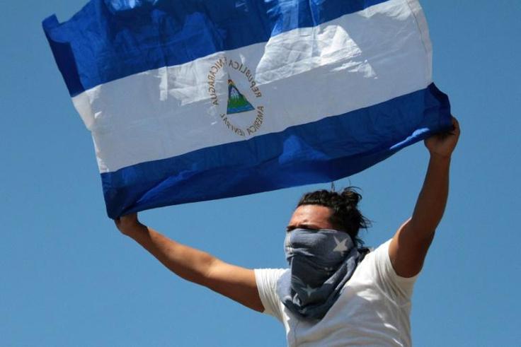 An opposition protester displays a Nicaraguan flag at a mall where he and others took refuge after they were prevented by riot police in Managua from demonstrating against the government to demand the release of those arrested for taking part in anti-g...