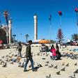 Libyans walk in the Tripoli's Martyr Square as fresh fighting flared south of the capital