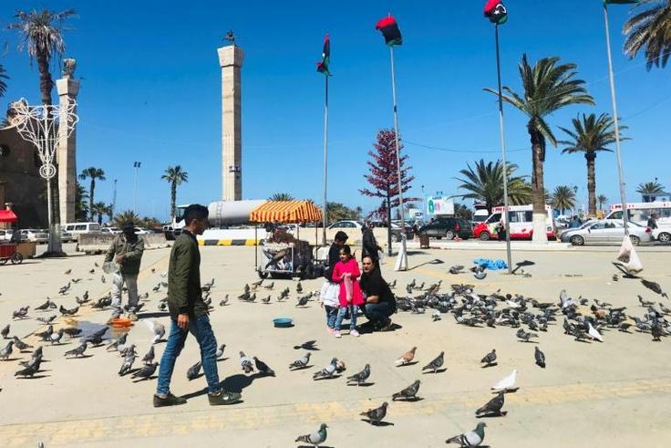Libyans walk in the Tripoli's Martyr Square as fresh fighting flared south of the capital