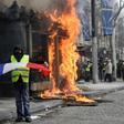 A Yellow Vest protester waves a French flag as fire rages on the Champs-Elysees on Saturday