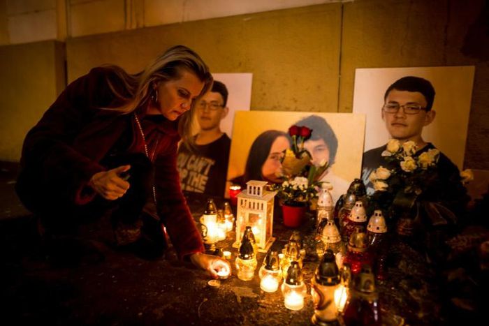 A woman (pictured February 2019) places candles next to a memorial for journalist Jan Kuciak and his fance Martina Kusnirova, who were gunned down in their home in February 2018