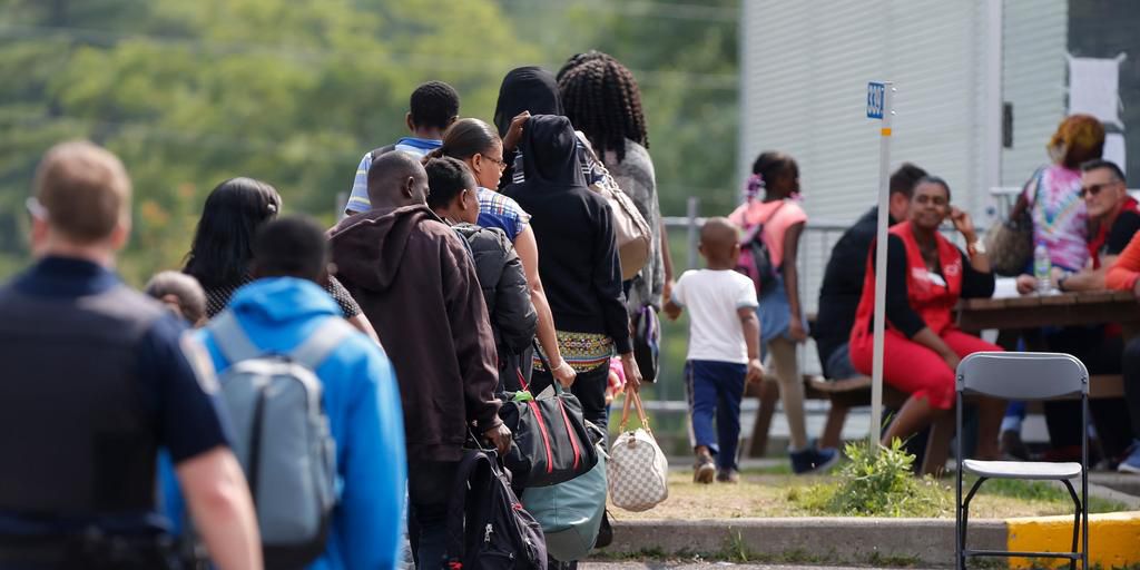 A group of asylum seekers wait to be processed after being escorted from their tent encampment to the Canada Border Services in Lacolle, Quebec, Canada August 11, 2017.