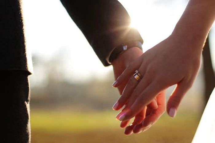 Wedding couple holding hands on sunset background shot in slow motion (Shutterstock)