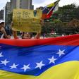 Opposition supporters demonstrate behind a Venezuelan national flag in the neighborhood of Los Palos Grandes in Caracas, on March 31, 2019