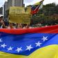 Opposition supporters demonstrate behind a Venezuelan national flag in the neighborhood of Los Palos Grandes in Caracas, on March 31, 2019