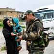 A Syrian soldier checks the identification documents of a woman crossing from rebel-held areas in Idlib province into regime-held territories