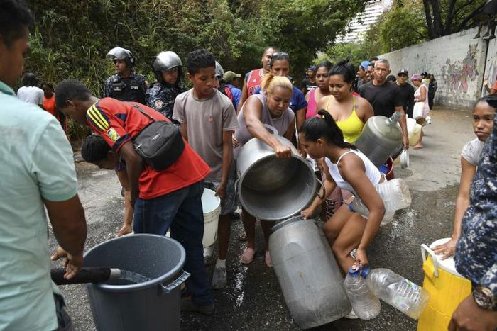 Venezuelan police help organize the distribution of drinking water in Caracas during a power outage that has affected millions already struggling with dire economic hardship