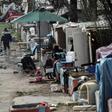 Members of the Roma community stand in a camp that was attacked during the night of March 25 in Bobigny, near Paris