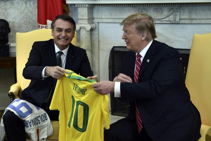 US President Donald Trump(R) and Brazilian President Jair Bolsonaro exchanged team jerseys during their meeting at the Oval Office in the White House