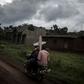 Toll: Three people on a motorbike carry a cross for a grave in Ebola-hit North Kivu