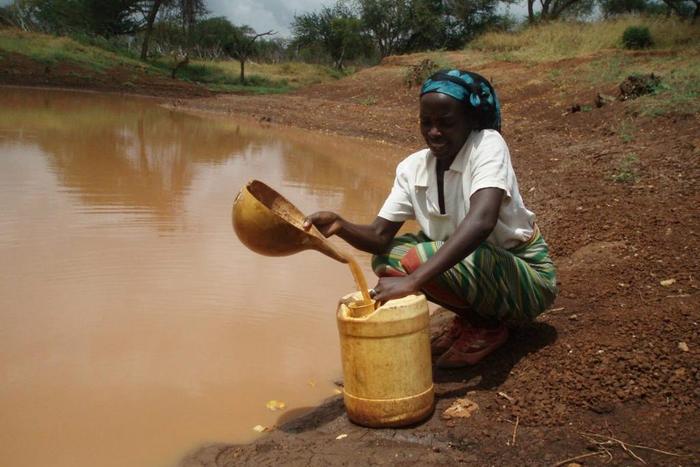 A woman scooping water from the river [africaqua]
