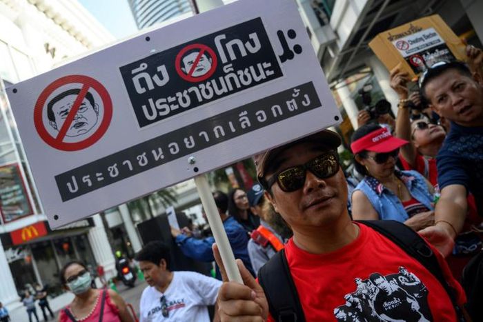A Thai anti-junta protester displays a placard during a demonstration in Bangkok on Sunday