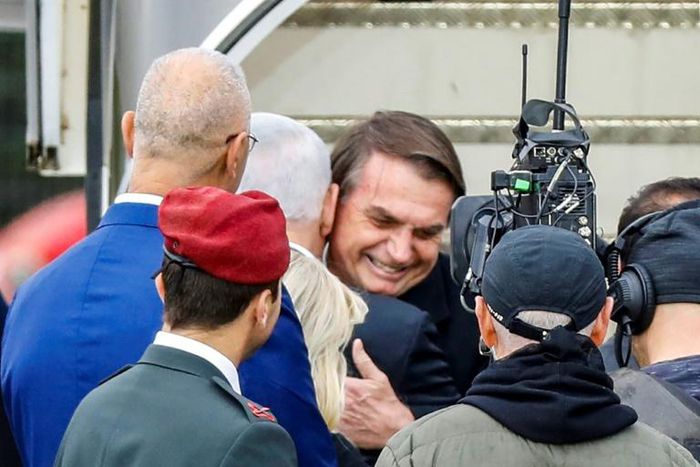 Brazilian President Jair Bolsonaro (C), seen here being embraced by Israeli Prime Minister Benjamin Netanyahu, is in Israel on a visit while at home protesters marched against his government
